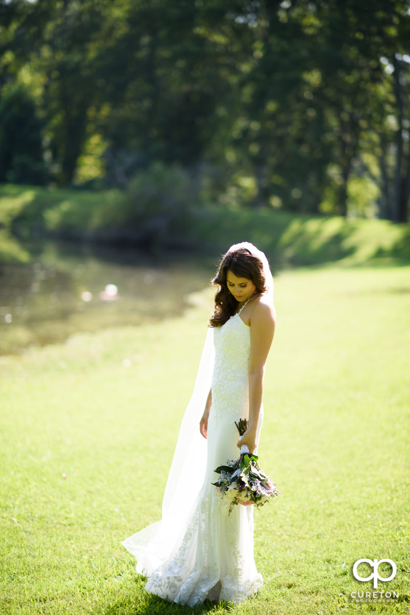 Bride standing beside a lake at Noah's Event Venue.