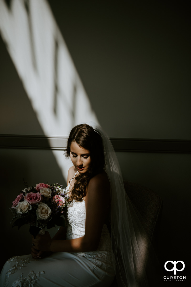 Bride sitting in a stream of light before her wedding at Noah's Event Venue in Greenville,SC.