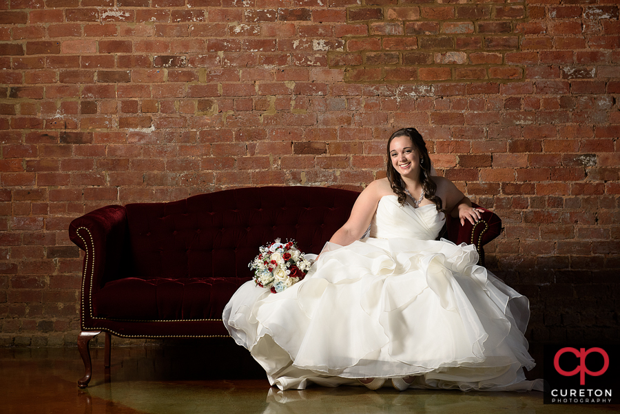 Bride sitting on a vintage couch in The Old Cigar Warehouse in Greenville,SC.