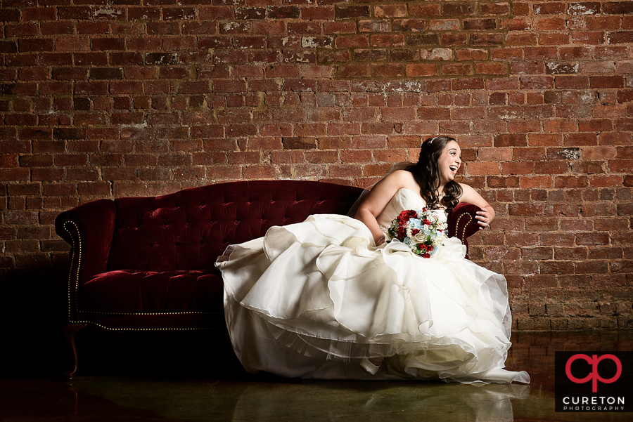 Bride laughing on a vintage couch.