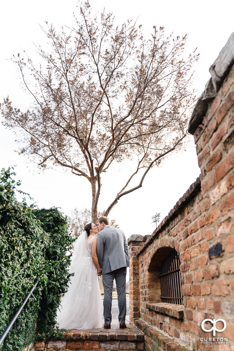 Man kissing his bride at the top of a staircase after their wedding ceremony at The Old Cigar Warehouse in Greenville,SC.