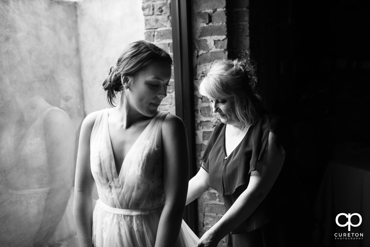 Bride's mother helping her into her dress.