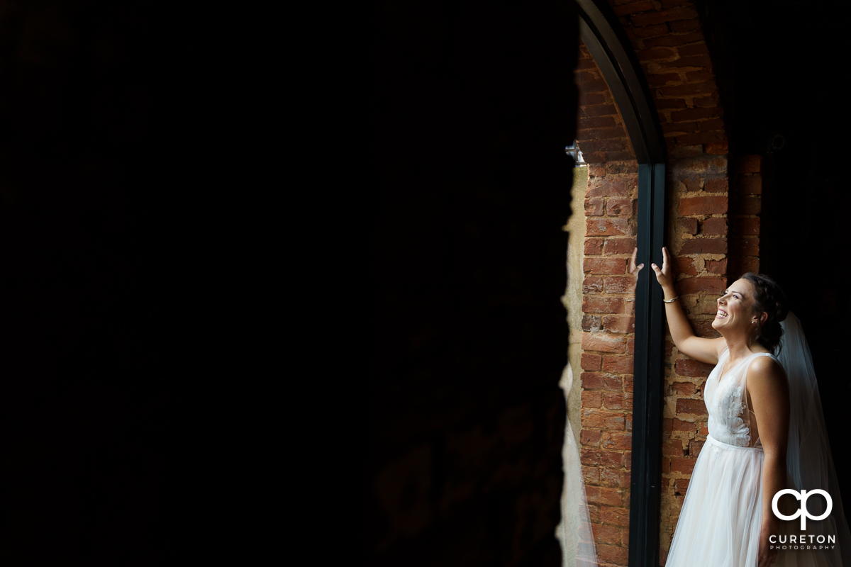 Bride laughing while looking out the window.