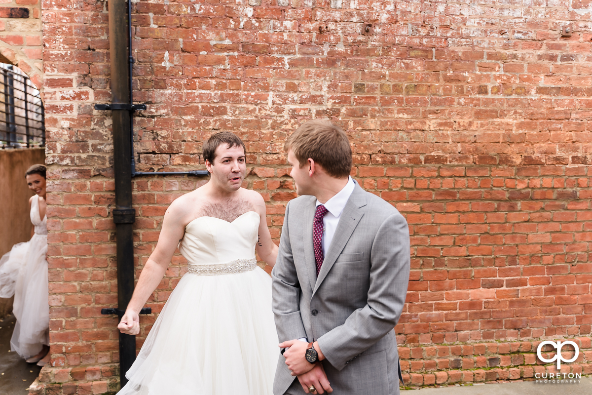 Groomsmen in a wedding dress showing up to the first look to trick the groom at The Old Cigar Warehouse.