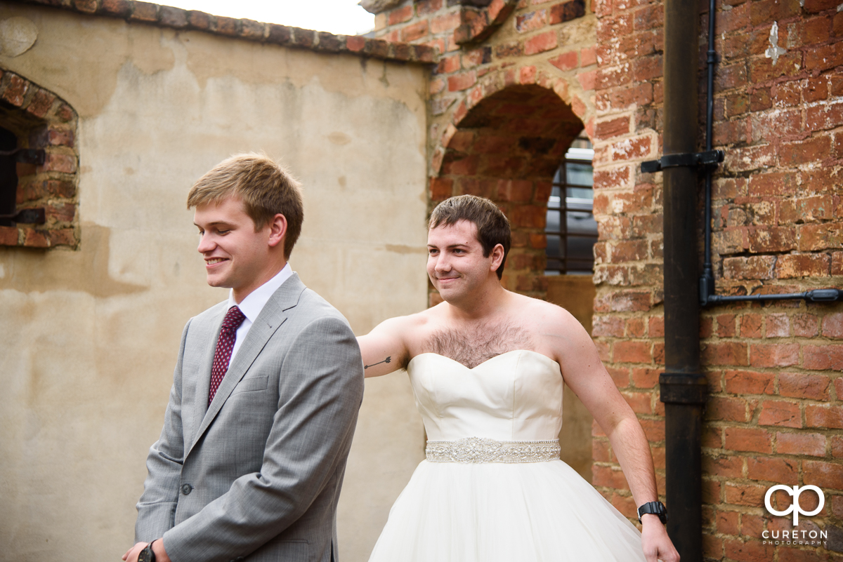 Groomsmen in a wedding dress showing up to the first look to trick the groom .