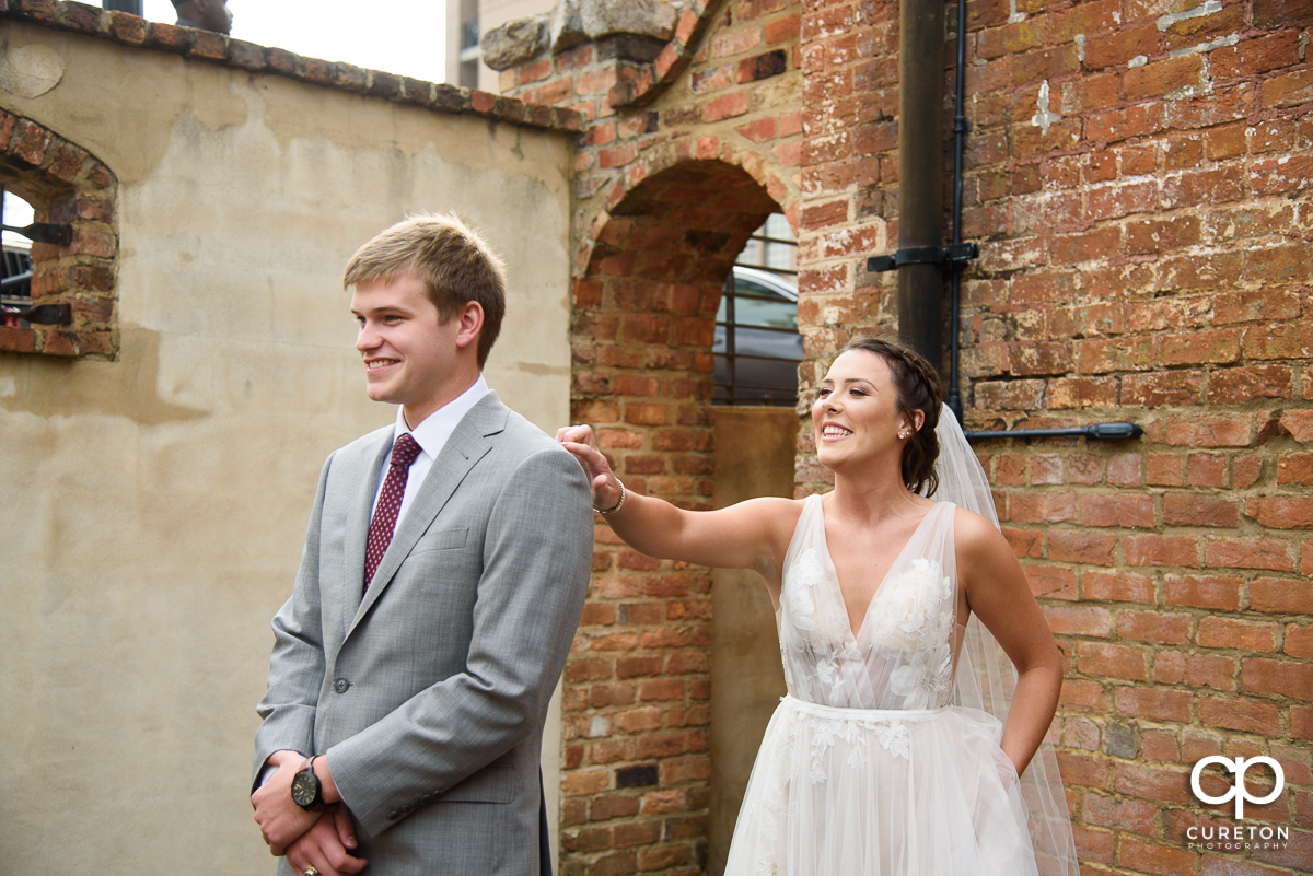 Bride tapping on the groom's shoulder at the first look.