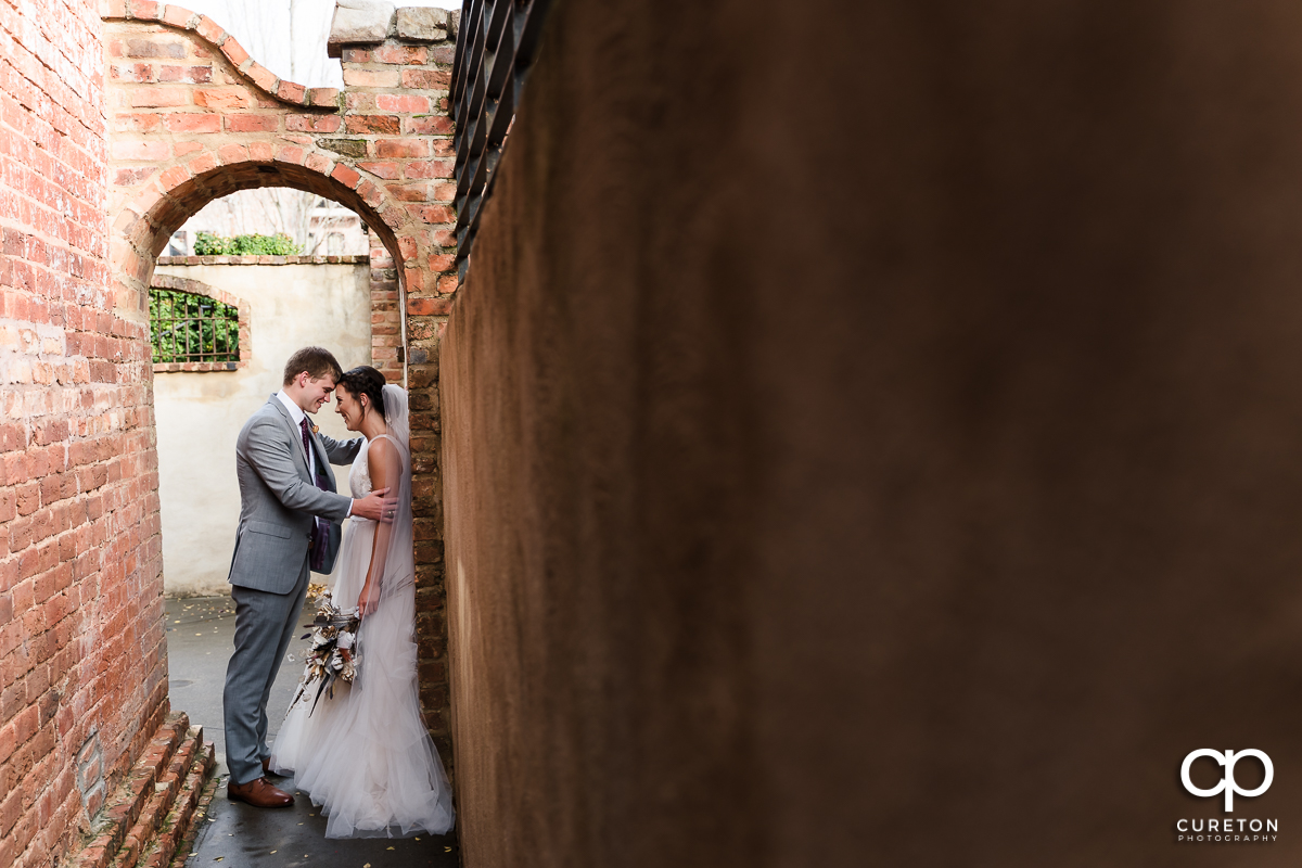 Bride and groom standing in an archway.