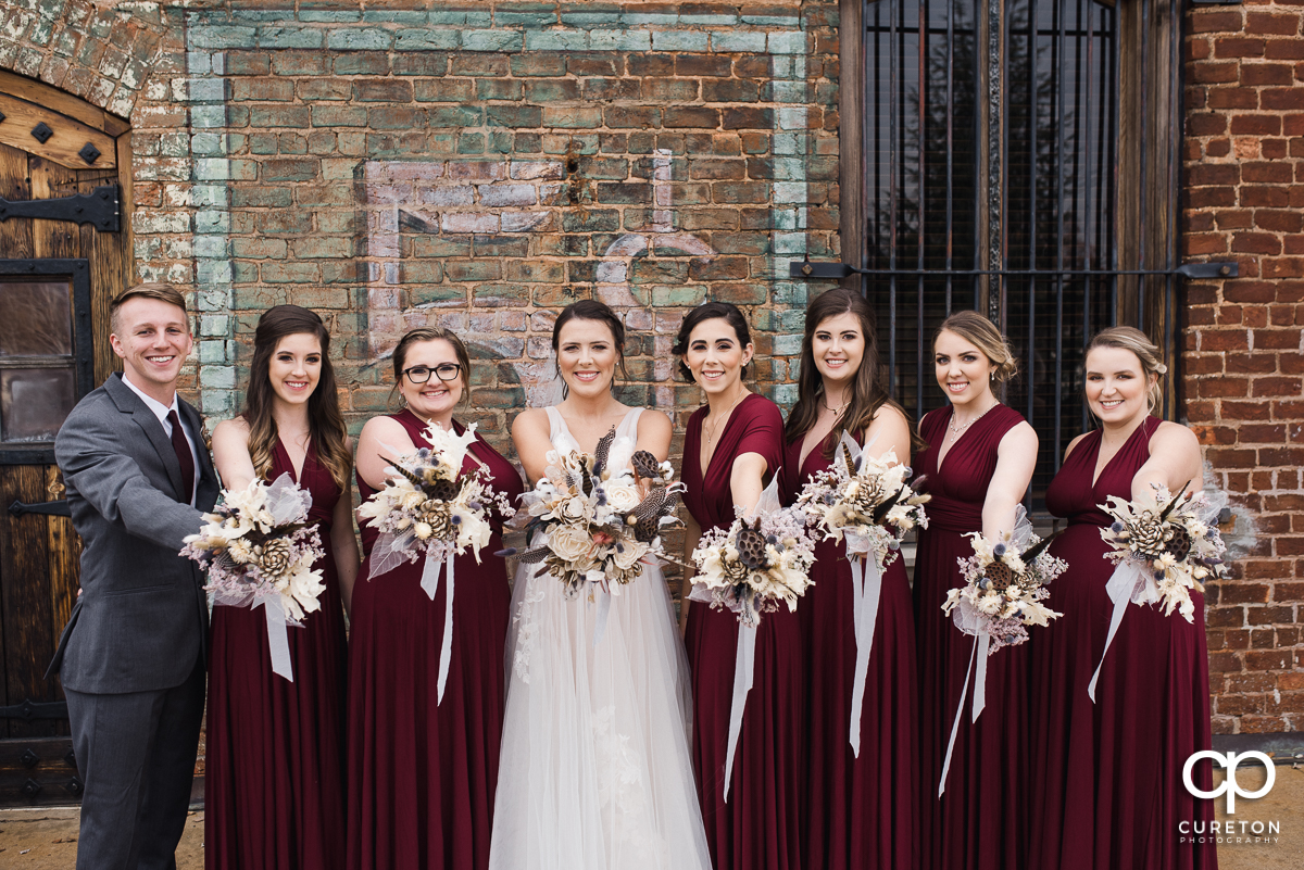 Bride and bridesmaids holding their flowers out.