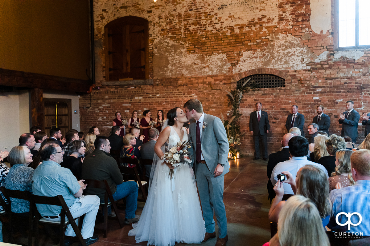 Bride kissing her groom as they walk back down the aisle.