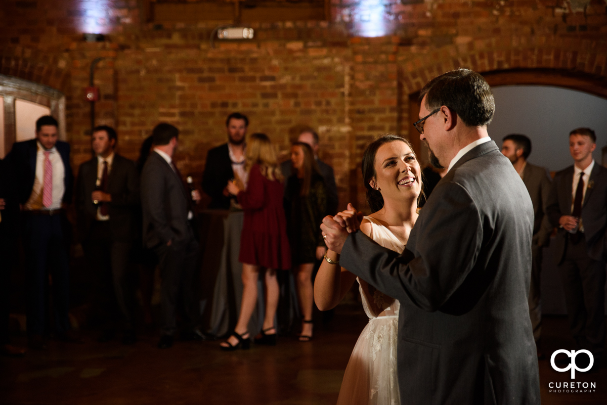 Bride smiling at her dad as the dance at the reception.