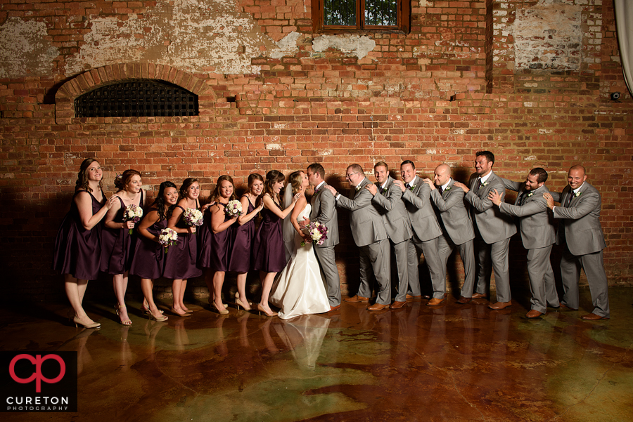 Wedding party pushing the bride and groom together.