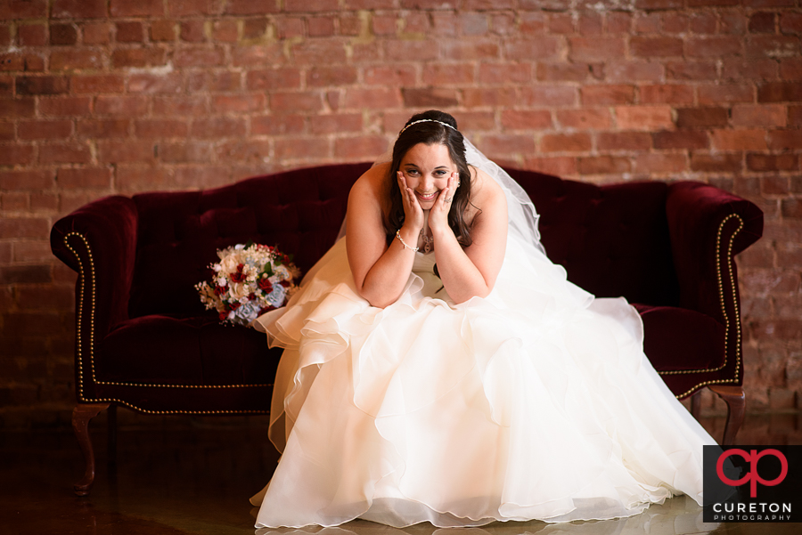 Bride sitting on a red couch during her Old Cigar Warehouse bridal session..