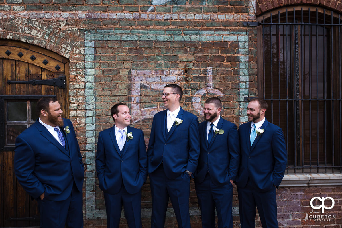 Groom laughing with his groomsmen on the deck of The Old Cigar Warehouse.