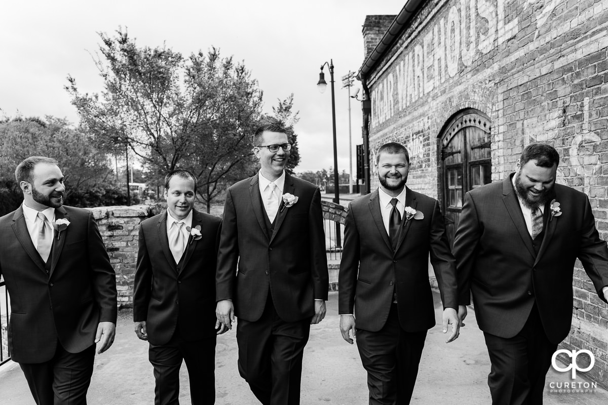 Groom walking with his groomsmen on the deck of The Old Cigar Warehouse.