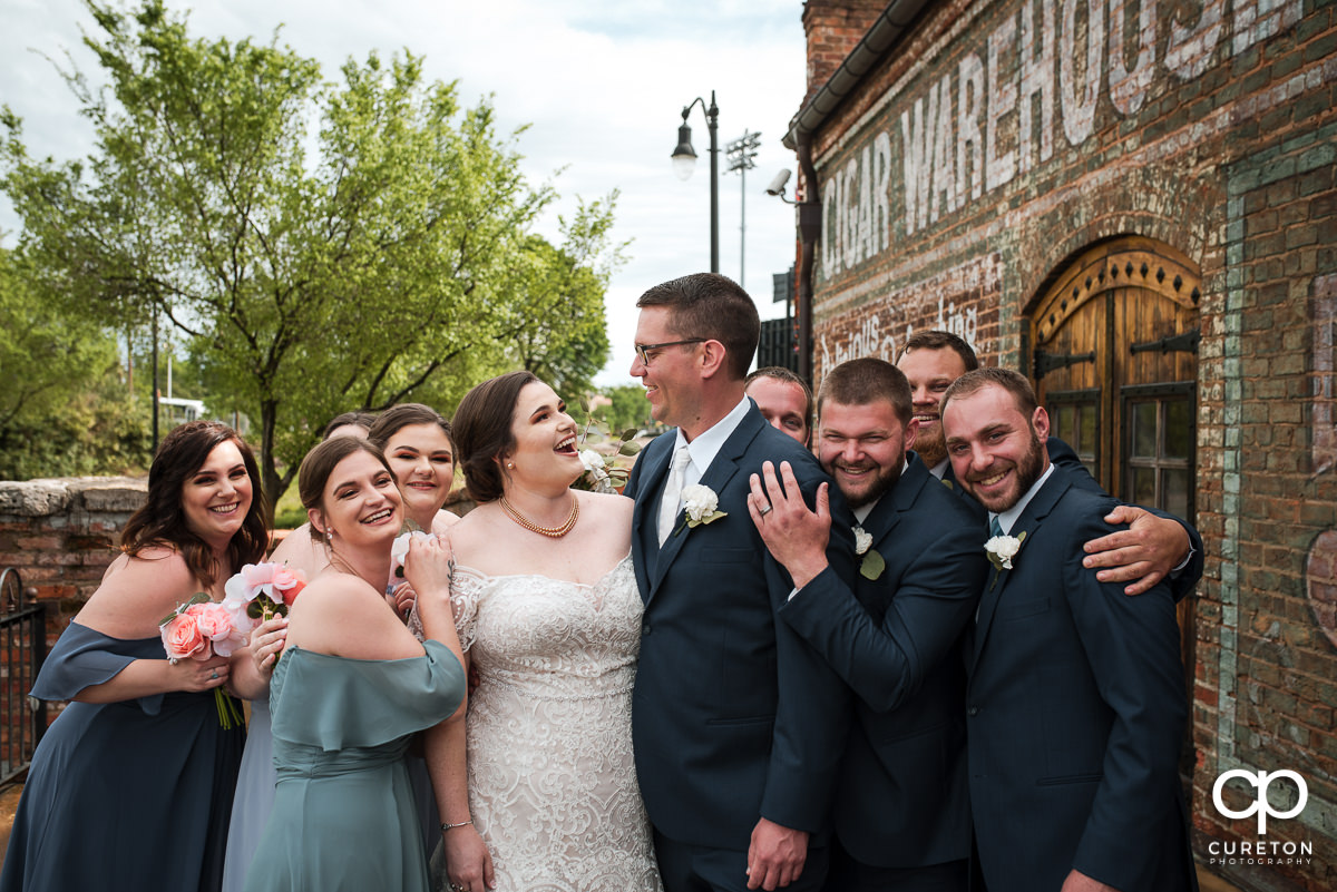 Bride and groom being hugged by the bridal party.