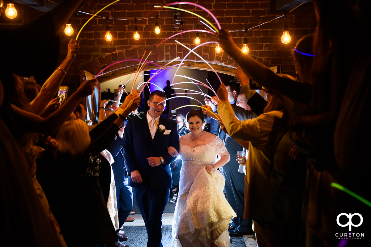 Bride and groom making a grand exit though glow sticks at The Old Cigar Warehouse wedding.