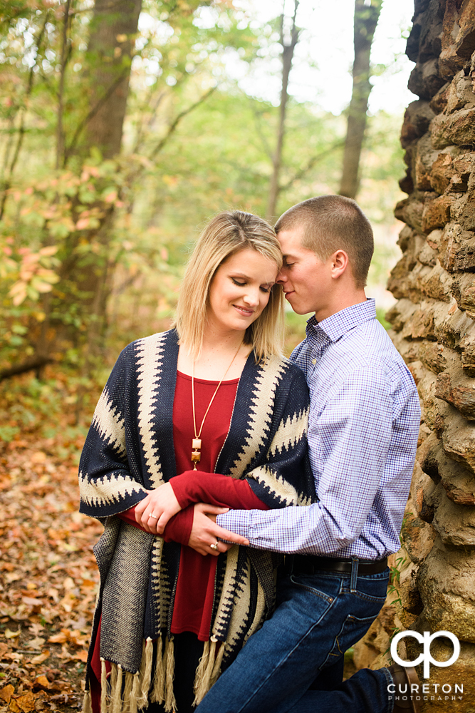 Man and his fiancée cuddling under the bridge at Paris mountain state park during their engagement session.