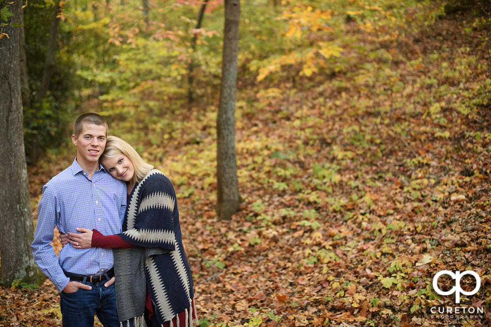 Briding groom hugging in the middle of the fall leaves .