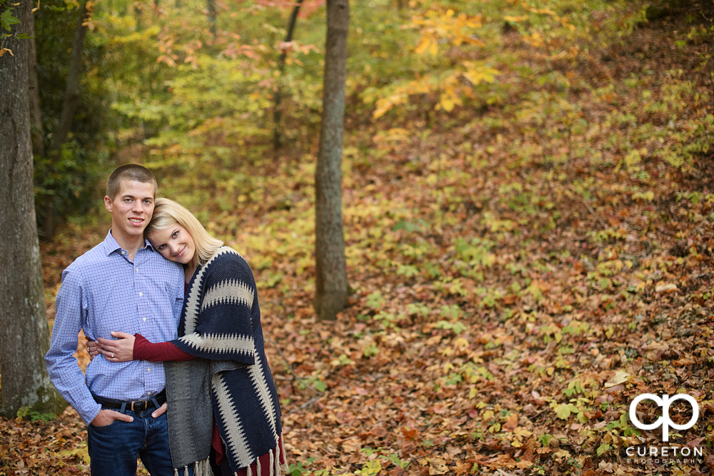 Briding groom hugging in the middle of the fall leaves .