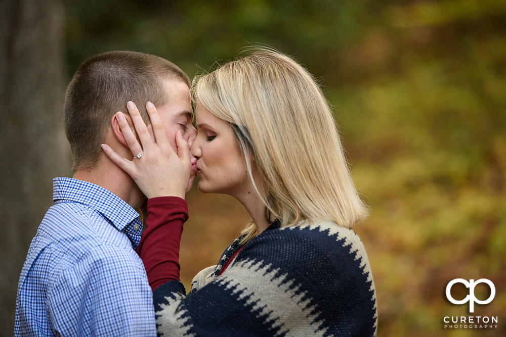 Woman kissing her fiancé during their engagement session.