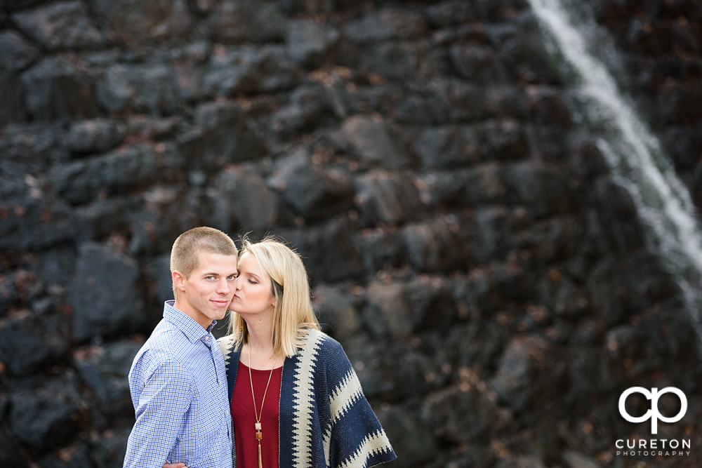 Future bride kissing her future groom at Paris mountain.
