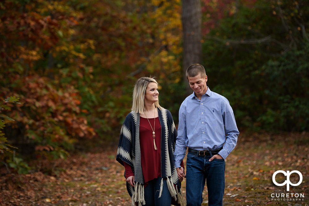 Engaged couple walking through the woods.