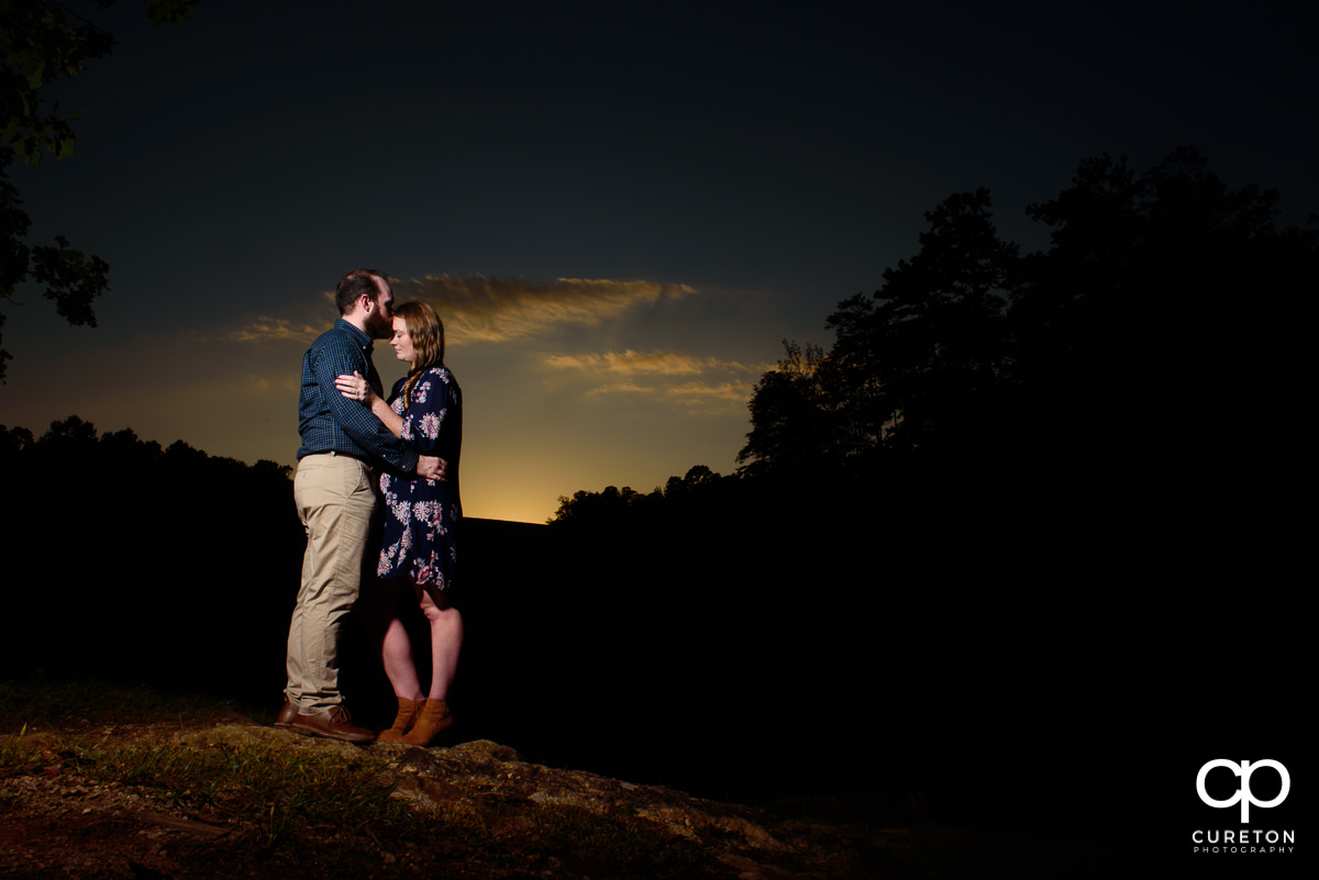Groom kissing his future bride on the forehead at sunset during an engagement session at Paris Mountain State Park in Greenville,SC.