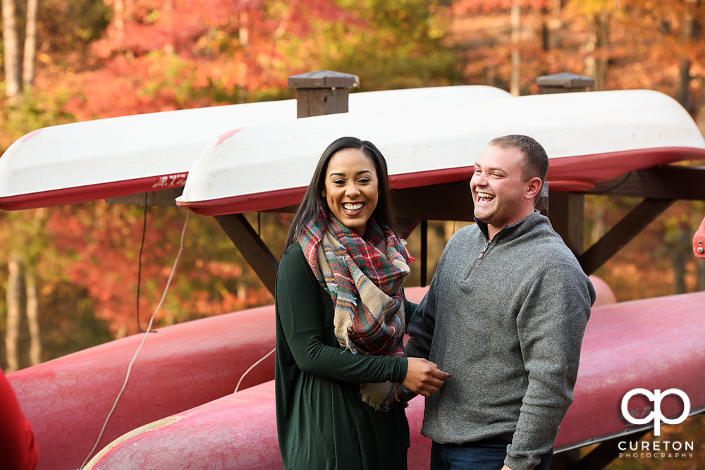 Engaged couple laughing by the boats on the pond during their Paris Mountain State Park Engagement Session in Greenville,SC.