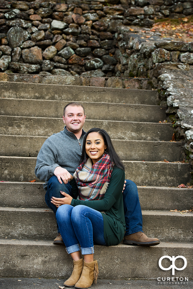 Engaged couple sitting on the steps.