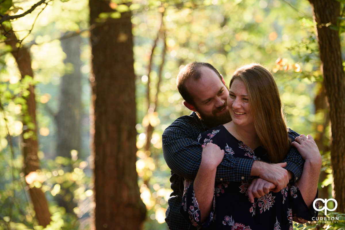 Bride and groom hugging in the woods during their engagement session.