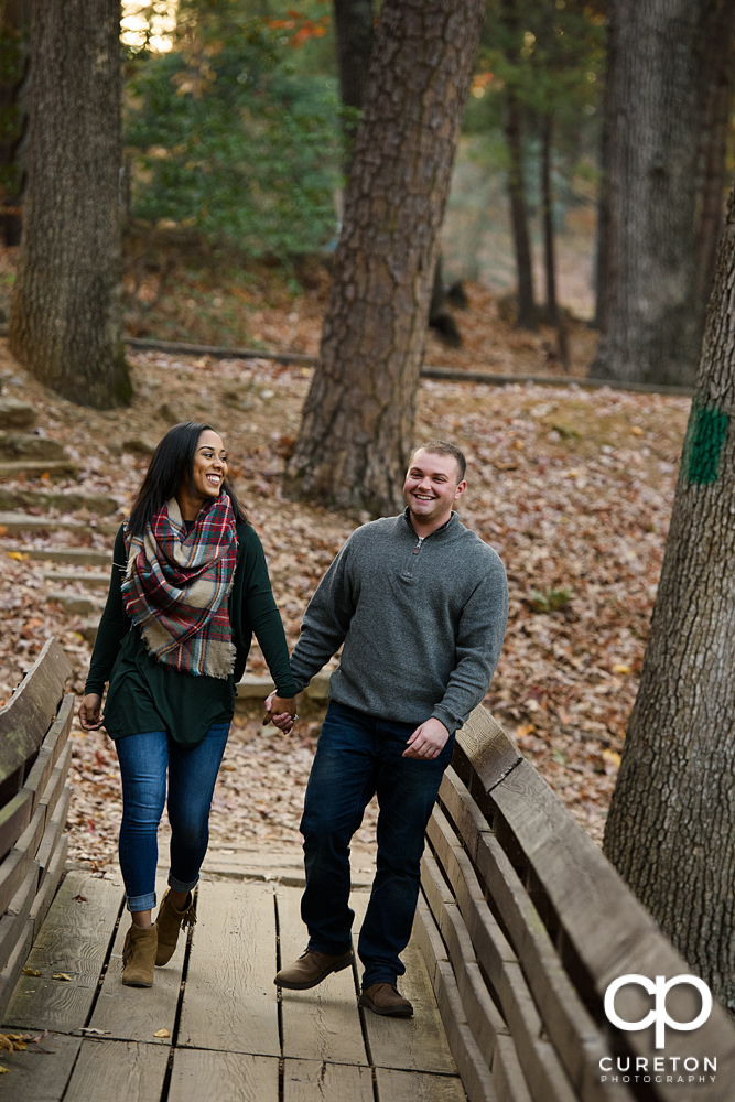 Engaged couple walking over the bridge at Paris Mountain.