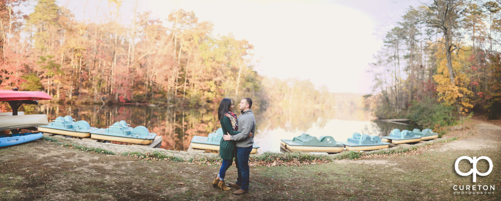 Panoramic engagement photo of a couple by the lake at Paris Mountain.