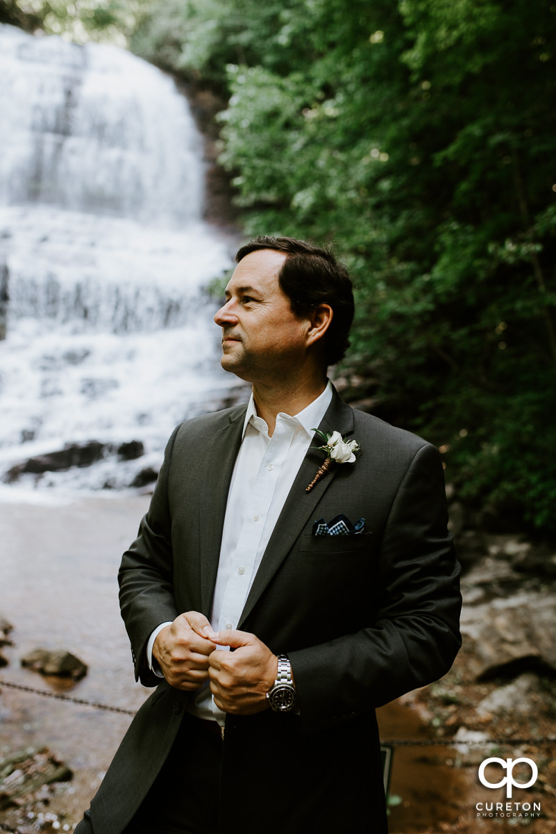Groom in front of a waterfall.