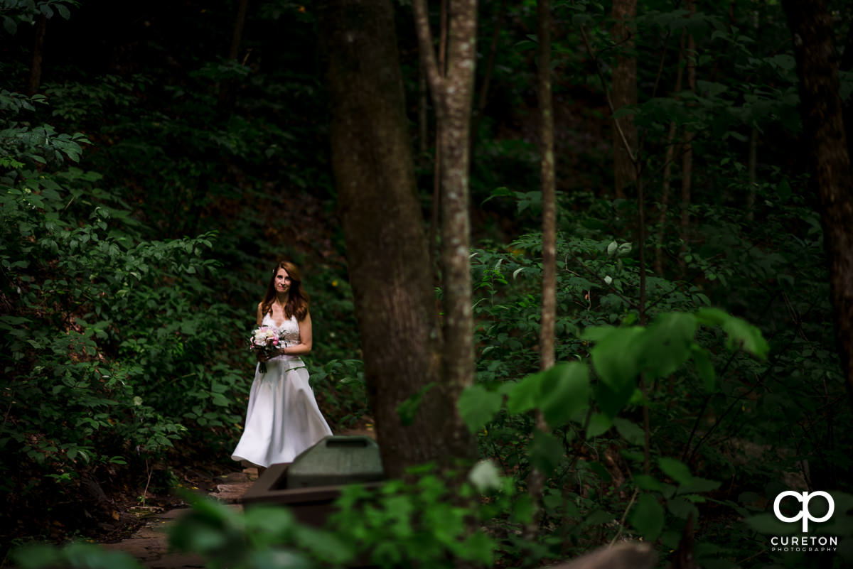 Bride walking down the aisle at her wedding ceremony at Pearson's Falls in North Carolina.