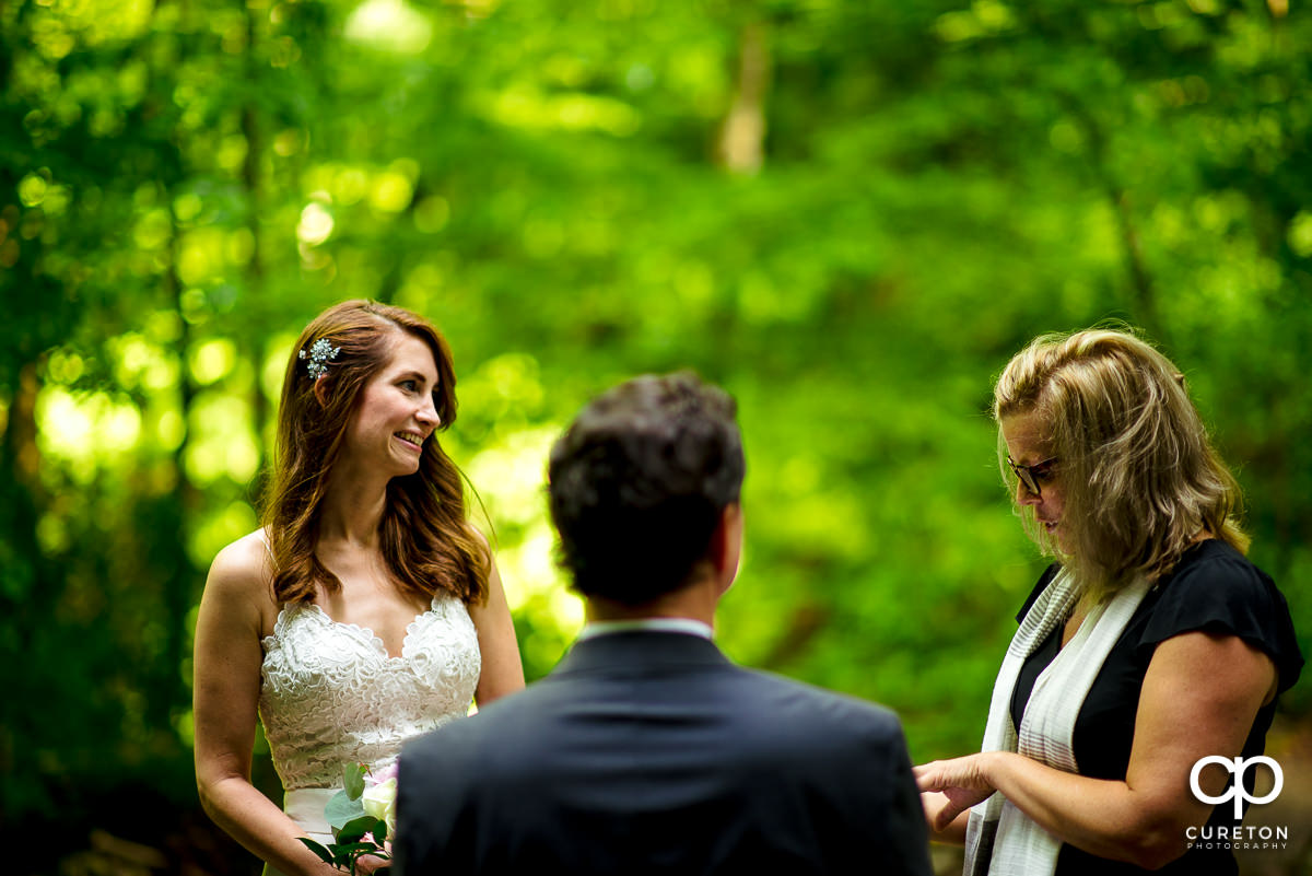 Bride smiling during the ceremony in the forest.