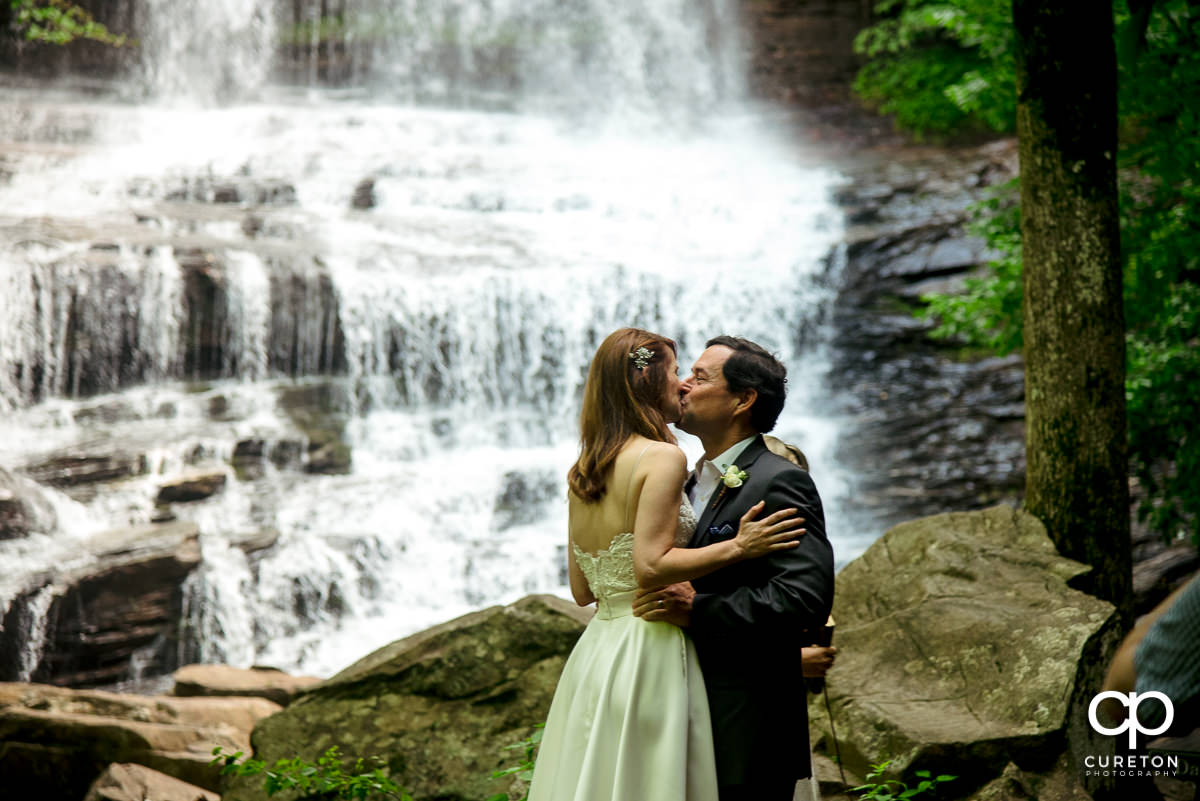 Bride and groom first kiss at the waterfall wedding in North Carolina.