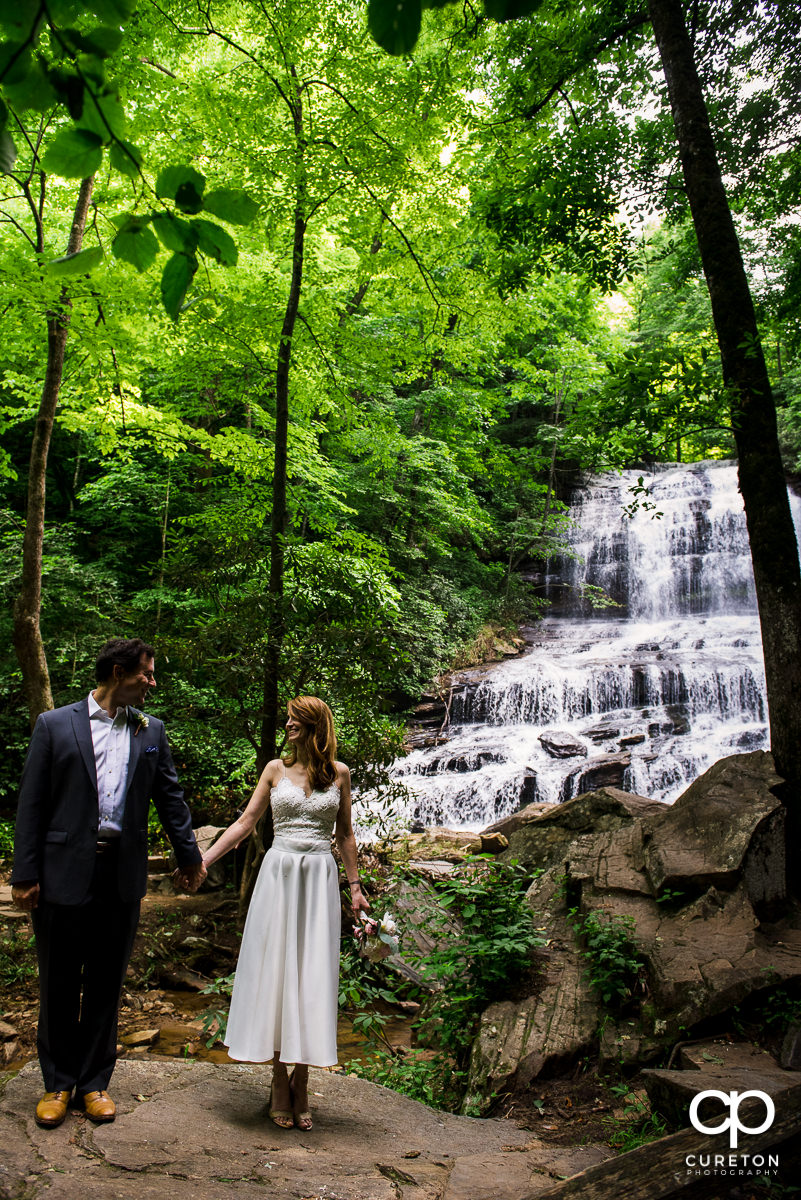 Bride and groom walking through the forest.