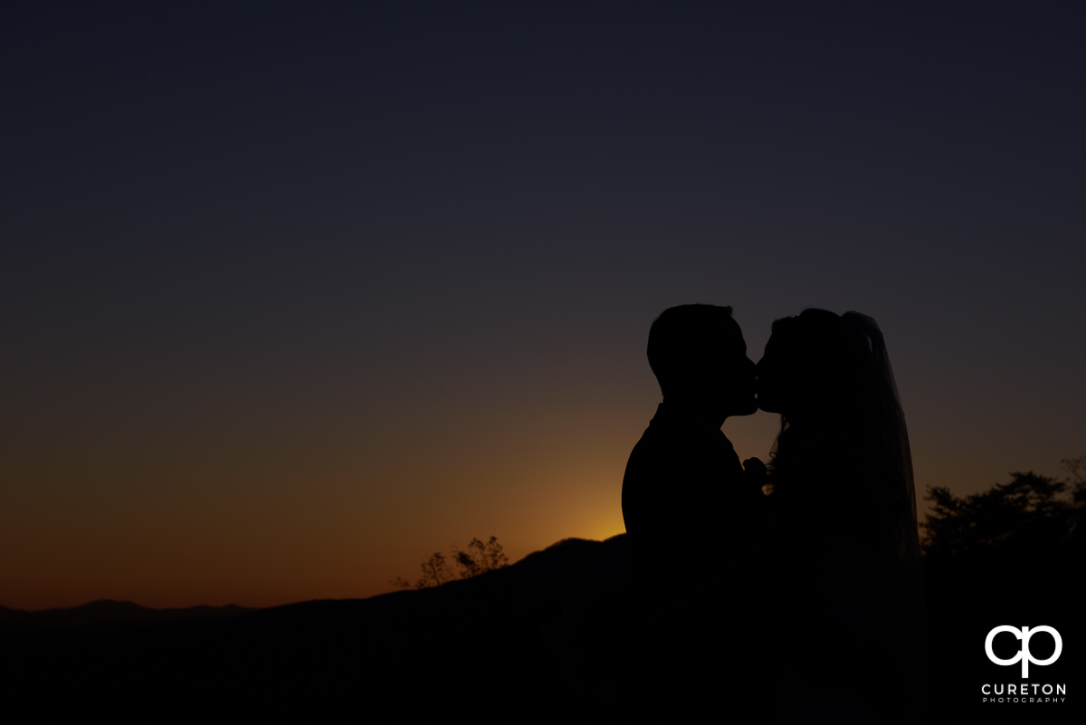 Bride and Groom kissing an sunset silhouette.