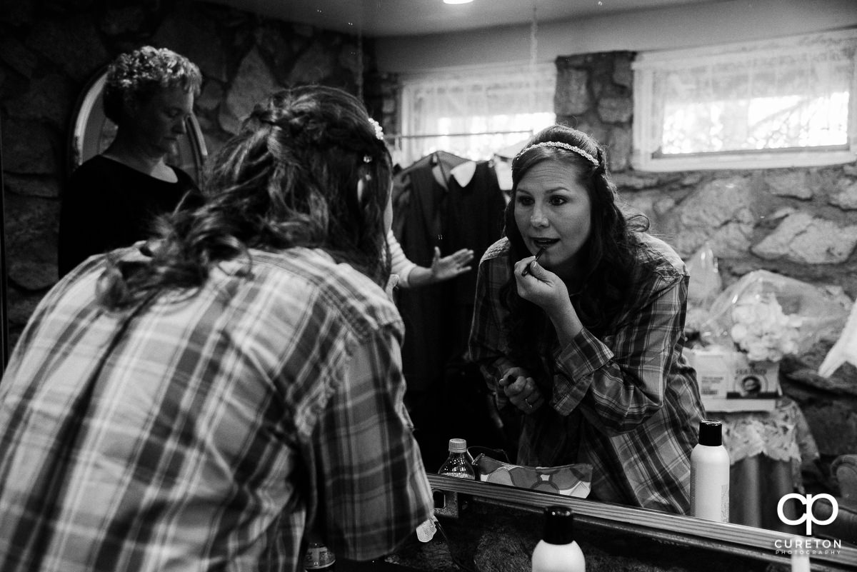 Bride putting on her makeup in the mirror.