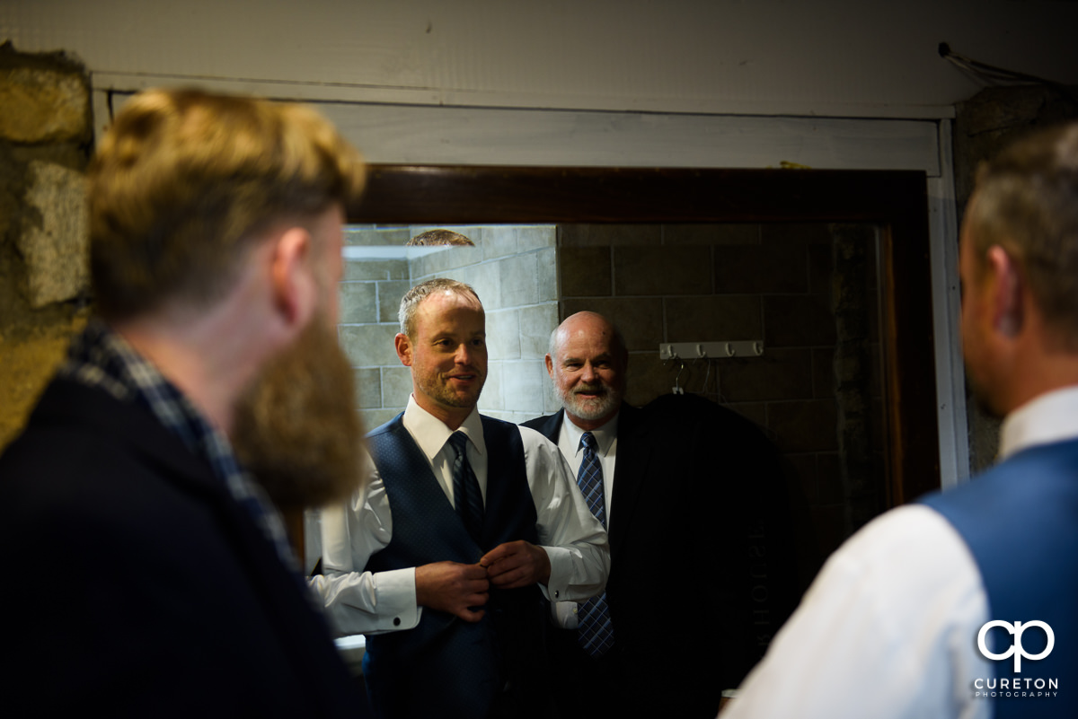 Groom buttoning his vest.