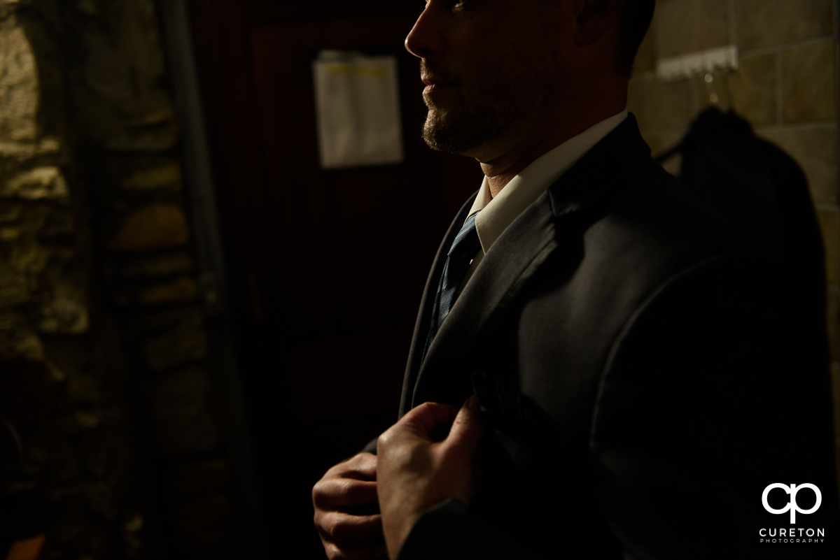 Groom buttoning his jacket.