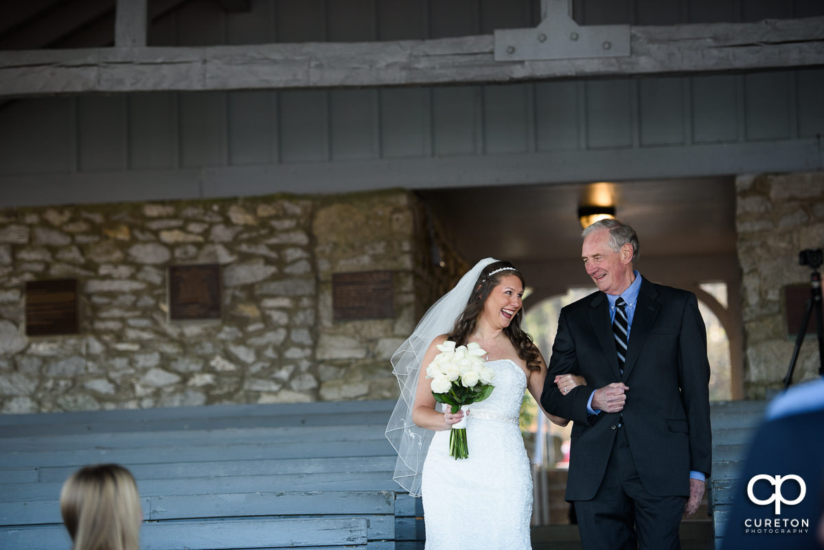 Bride and her father smiling walking down the aisle.