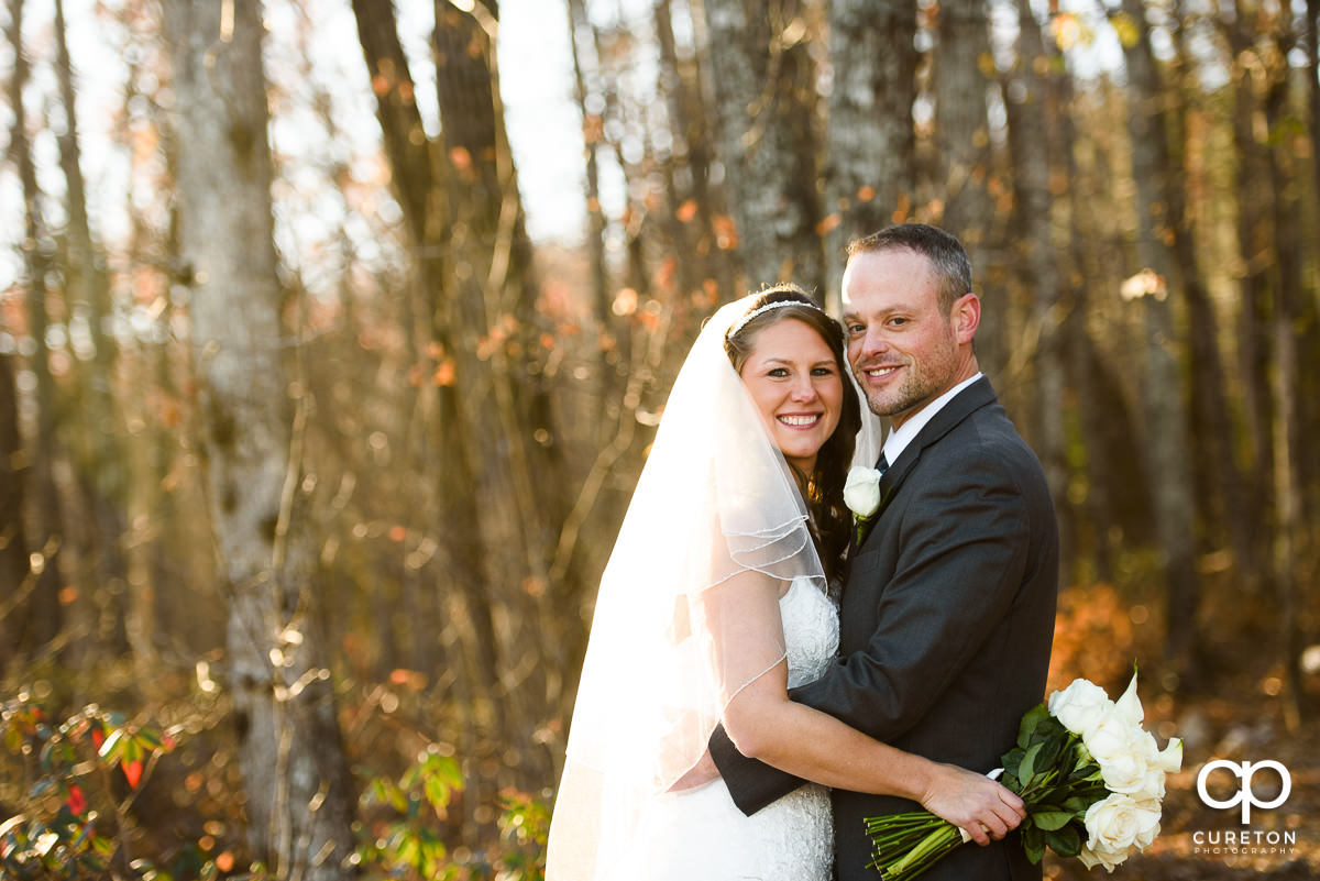 Smiling bride and groom in the woods.