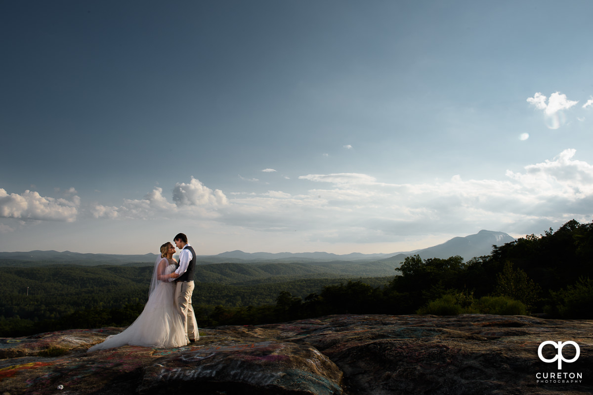 Bride and Groom on a cliff with the mountains in the background.