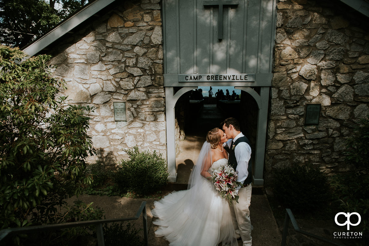 Bride and groom kissing at the doorway of Symmes Chapel after their wedding ceremony.