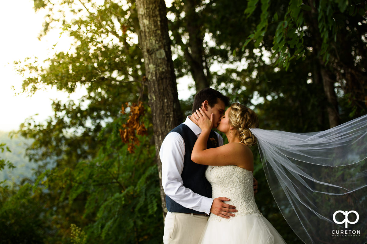 Bride holding groom as her veil blows in the breeze.