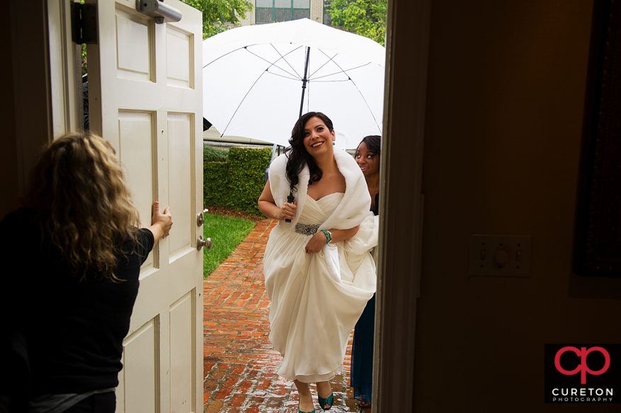 Bride holding umbrella entering the wedding venue.