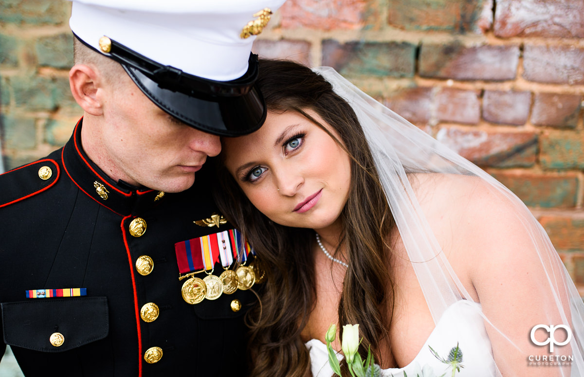 Bride and her Marine groom cuddling after their wedding ceremony.