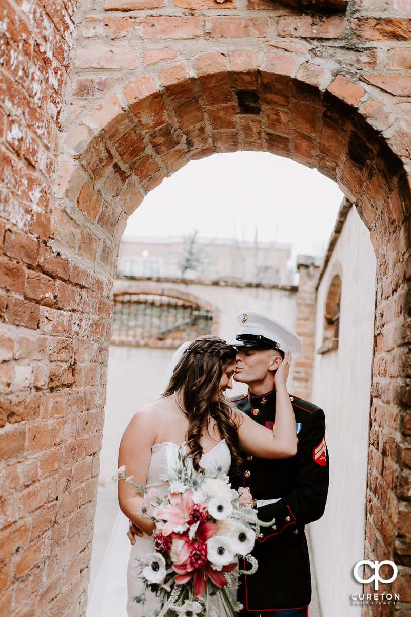 Bride and her Marine groom standing in an archway outside of the Old Cigar Warehouse after their wedding ceremony.
