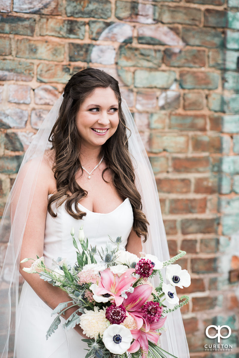 Pretty bride smiling holding a unique bouquet.